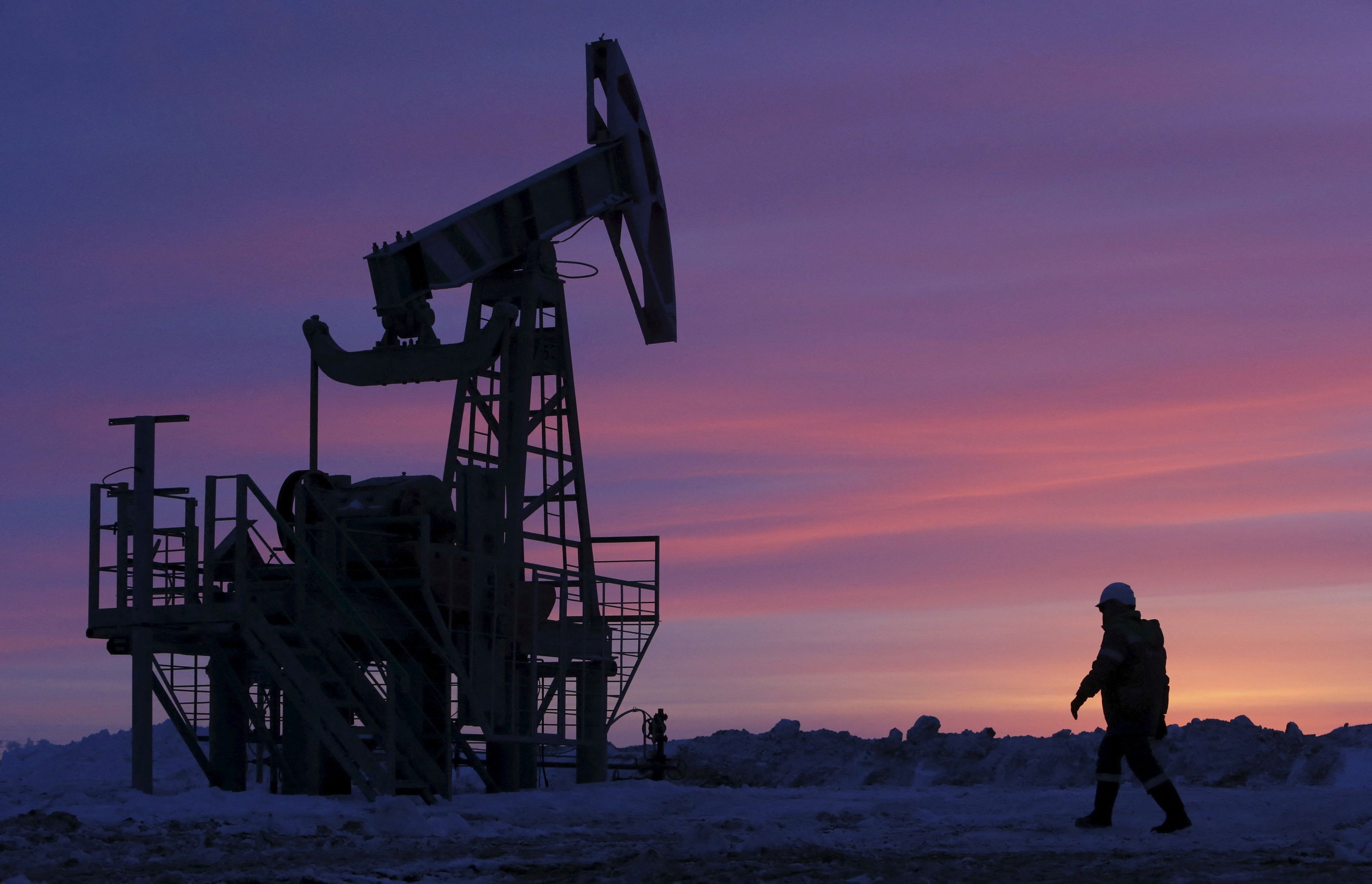 A worker passes by a pumping crane at an oil field owned by Bashneft near Nikolo Berezovka